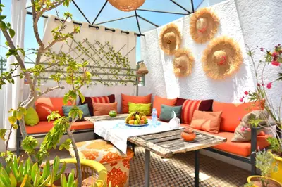 a patio with an orange couch and a table at Beldi House in Marrakech