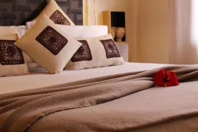 a close up of a bed with a red flower on it at VERY RARE APARTMENT GUELIZ CENTER OF Marrakech in Marrakech