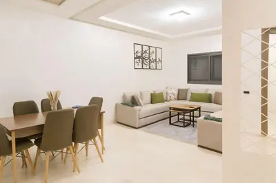 a living room with a table and chairs and a couch at Cozy Family Apartment 2BR Pool Parking Gueliz Marrakesh in Marrakech