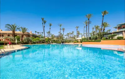 a large swimming pool in a resort with palm trees at Palmeraie vintage apartment with pool in Marrakech