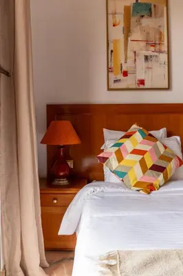 a bed with a wooden headboard next to a table with a lamp at Palmeraie vintage apartment with pool in Marrakech