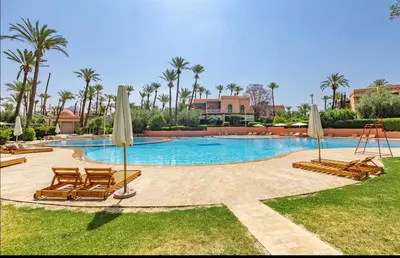 a swimming pool with chairs and umbrellas at Palmeraie vintage apartment with pool in Marrakech