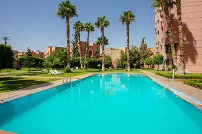 a large swimming pool with palm trees and a building at La Vita Moderna Marrakech Pool in Marrakech