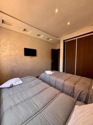 a bedroom with two beds and a tv on the wall at NEW Marrakech Pool Center - ONLY FAMILY in Marrakech