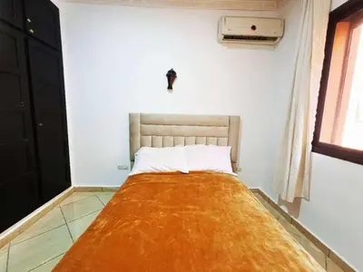 a bedroom with a bed with an orange blanket on it at Homes 365 Residence Caricia in Marrakech