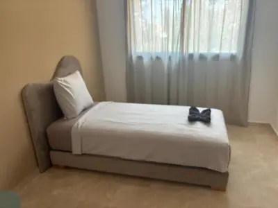 a bedroom with a bed with a chair and a window at Beautiful 5 bedroom duplex! Pool! in Oulad Akkou