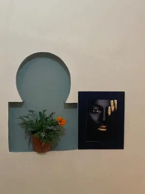 a picture of a face on a wall with a plant at Riad Massin Marrakech in Marrakech