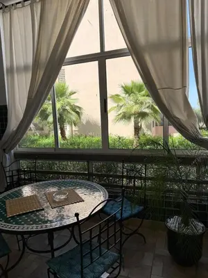 a table and chairs in a room with a large window at Riad Garden Apartement & WiFi & Pool & Parking in Marrakech