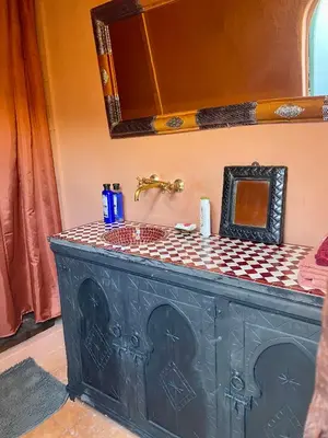 a black bathroom vanity with a mirror and a sink at Riad Sylvia in Marrakech