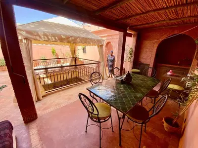 a man standing on a patio with a table and chairs at Riad Sylvia in Marrakech