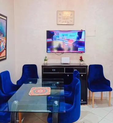 a dining room with a glass table and blue chairs at Appartement Marrakech à 10 minutes de l'aéroport in Marrakech