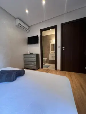 a bedroom with a large white bed and a television at Appartement neuf & moderne avec clim, piscine & balcon,Proche Jemaa el-Fna & Guéliz in Marrakech