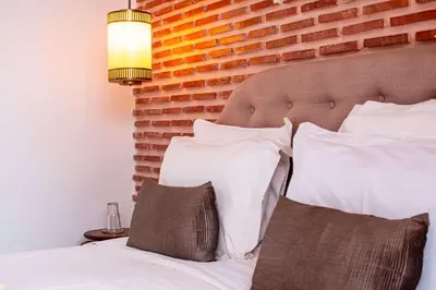 a bed with white pillows and a brick wall at Riad la Source du Desert in Marrakech