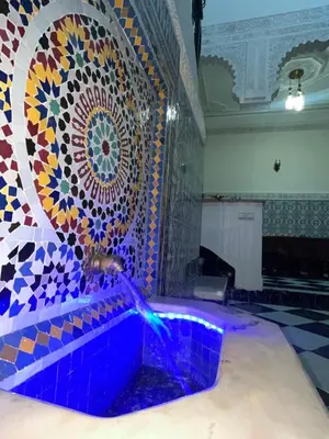 a fountain in a room with a mosaic wall at Riad Mounaf in Marrakech