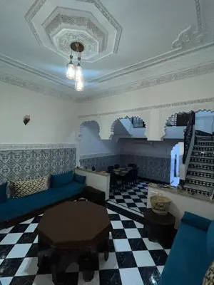 a living room with blue furniture and a checkered floor at Riad Mounaf in Marrakech