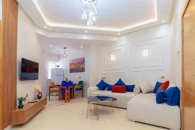 a living room with a white couch and blue pillows at Appart VIP 5 étoiles et romantique à Guéliz avec Piscine, Clim, Parking et Wifi haut débit 200 Mb in Marrakech