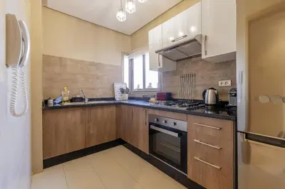a kitchen with wooden cabinets and a stove top oven at Beautiful 3 bedroom apartment for 6 people Prestigia Golf Saphir in Marrakech