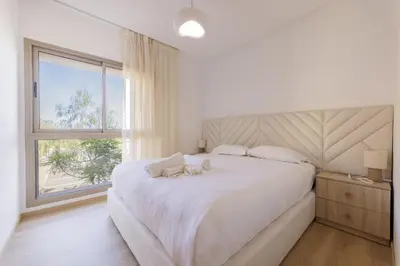 a white bedroom with a large bed and a window at Beautiful 3 bedroom apartment for 6 people Prestigia Golf Saphir in Marrakech