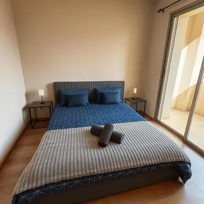 a bedroom with a bed with blue pillows and a large window at Appartement prestigia Marrakech in Marrakech