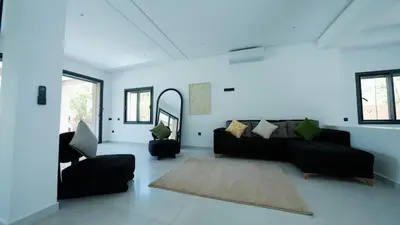 a living room with a black couch and chairs at Villa Adam in Oulad Akkou