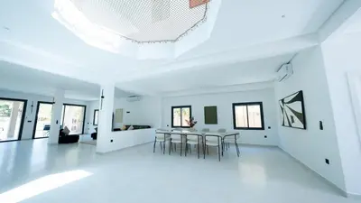 a white living room with a table and chairs at Villa Adam in Oulad Akkou