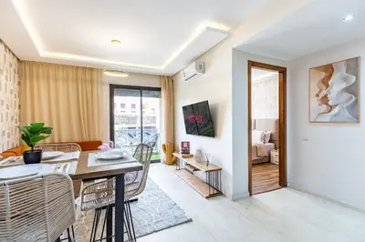 a dining room and living room with a table and chairs at Gueliz Stay modern apt in Marrakech