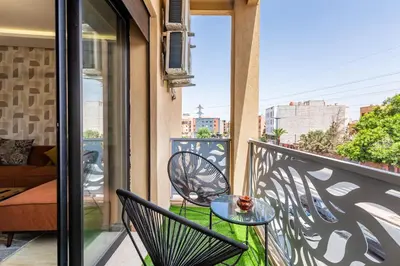 a balcony with a glass table and chairs at Gueliz Stay modern apt in Marrakech