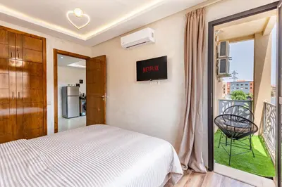 a bedroom with a bed and a window with a chair at Gueliz Stay modern apt in Marrakech