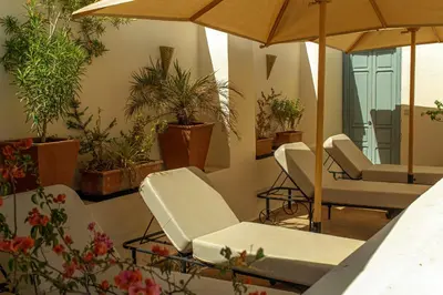a room with chairs and umbrellas and potted plants at Riad Dar Ben Slimane in Marrakech