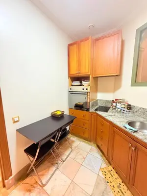 a kitchen with wooden cabinets and a black counter top at 2 - Bed Apartment with Garden & shared Pool - Moroccan - Modern Style in Marrakech