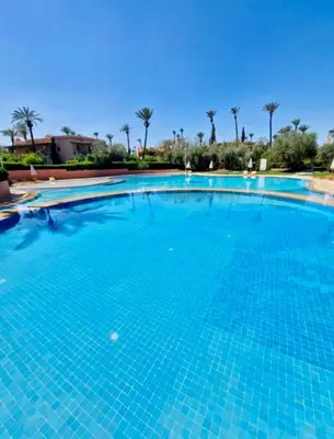 a large swimming pool with blue water at 2 - Bed Apartment with Garden & shared Pool - Moroccan - Modern Style in Marrakech