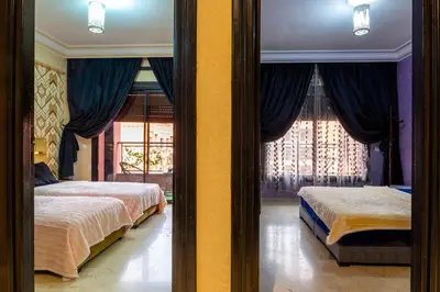 two beds in a bedroom with blue curtains at Apartment for rent Wintering in Marrakech