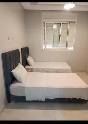 two beds in a room with a chair and a window at Chambre Marrakech 4 in Marrakech