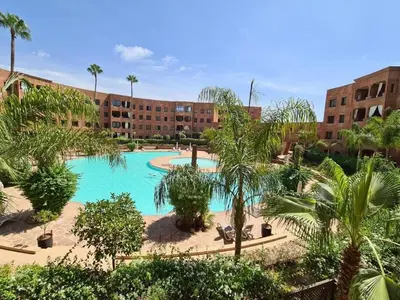 a resort with a swimming pool with palm trees and buildings at Palm river marrackech in Marrakech
