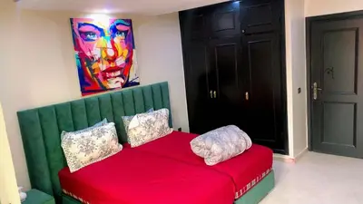 a room with a red couch with a painting on the wall at Le Nid de Vacances in Marrakech