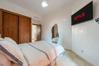 a bedroom with a bed and a tv on the wall at Le Berber - Complexe - Piscine - Fitness - Jeux in Marrakech