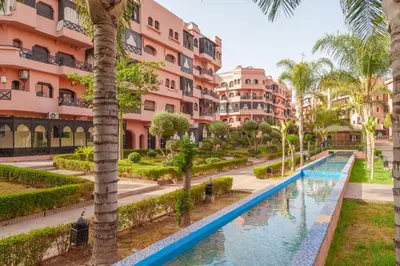a resort with a swimming pool and palm trees at Le Berber - Complexe - Piscine - Fitness - Jeux in Marrakech