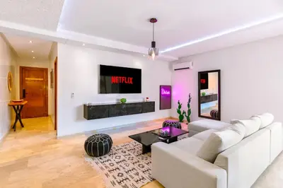 a living room with a couch and a tv on a wall at Studio avec piscine et lumières d'ambiance in Marrakech