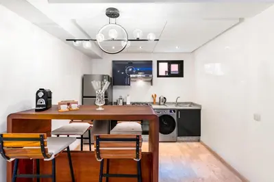 a kitchen with a wooden table and chairs in a room at Studio avec piscine et lumières d'ambiance in Marrakech