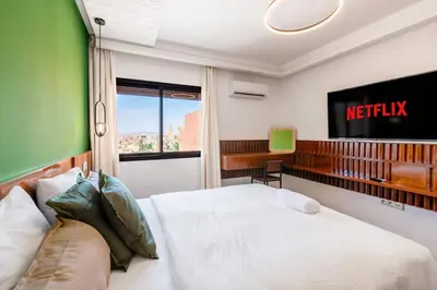 a bedroom with a bed and a tv on the wall at Studio avec piscine et lumières d'ambiance in Marrakech