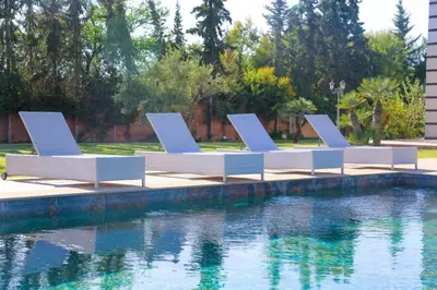 a row of chairs next to a pool of water at Villa Patel in Marrakech