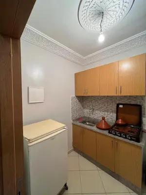 a kitchen with wooden cabinets and a white refrigerator at Appartement Marrakech au 1er étage in Marrakech
