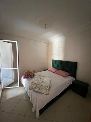 a bedroom with a bed with a green headboard and a window at Appartement Marrakech au 1er étage in Marrakech