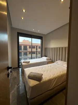 two beds in a room with a large window at Appartement Gueliz Elite garden in Marrakech