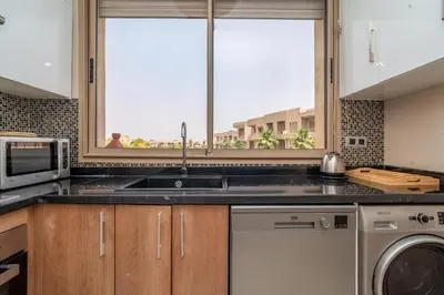 a kitchen with a sink and a microwave at Chic & Cozy Apartment with Pool View - Prestigia in Marrakech