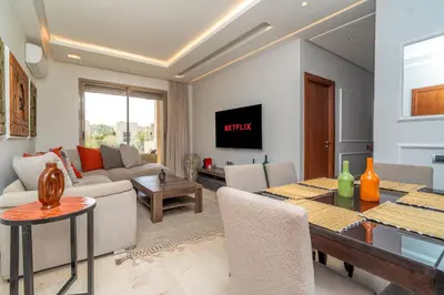 a living room with a table and a dining room at Chic & Cozy Apartment with Pool View - Prestigia in Marrakech