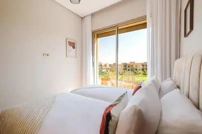 a bedroom with a bed and a large window at Appartement de charme residence avec piscine WiFi in Marrakech