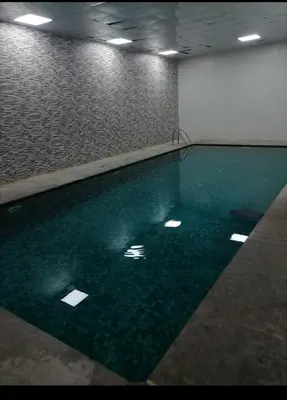 a swimming pool in a room with green water at jnane ali akioud Gueliz in Marrakech