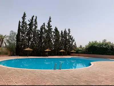 a large swimming pool with umbrellas and trees at Élégance & fraîcheur Appart avec piscine in Marrakech