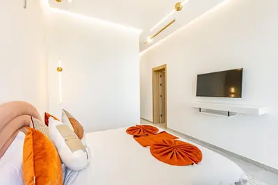 a bedroom with a bed with orange pillows and a tv at Villa Luxe Neuve , Piscine XXL , Sans vis-à-vis in Marrakech